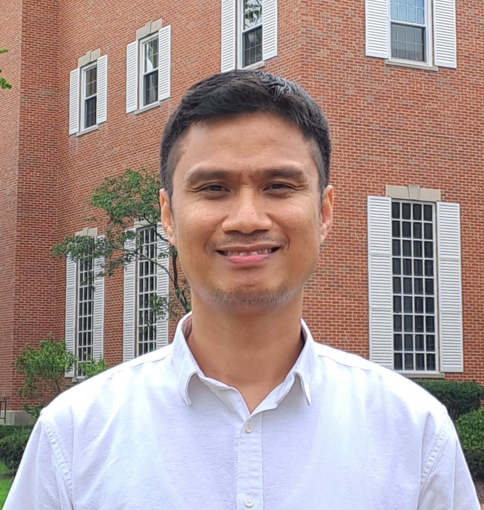 Student smiling in front of a brick building Student smiling in front of a brick building